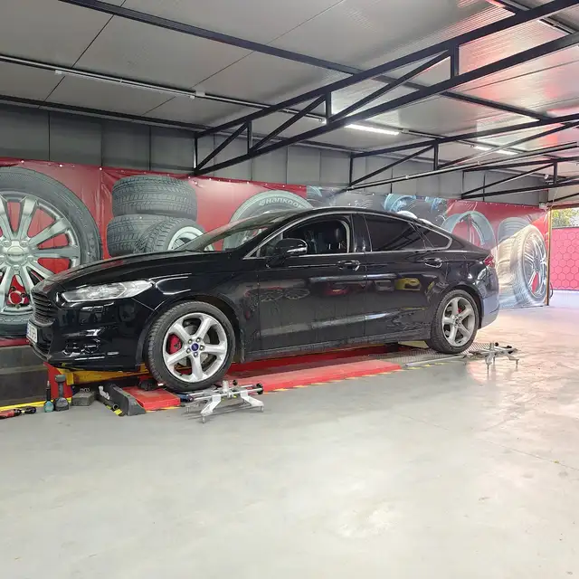 Ford Mondeo negru pe elevatorul de geometrie.